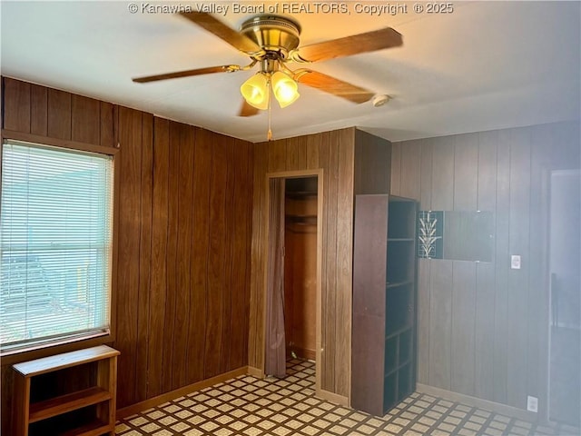 interior space featuring ceiling fan, wooden walls, and a closet