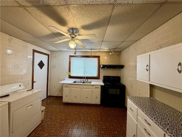 kitchen with black range with electric stovetop, separate washer and dryer, sink, and white cabinets