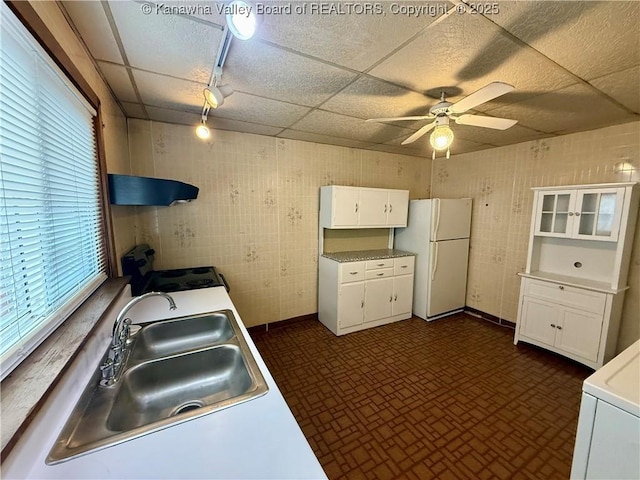 kitchen featuring white refrigerator, a paneled ceiling, sink, and white cabinets