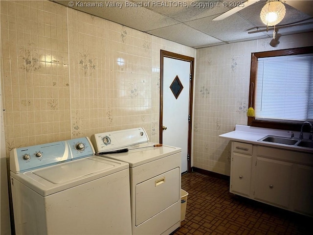 clothes washing area featuring sink, tile walls, washing machine and clothes dryer, and ceiling fan