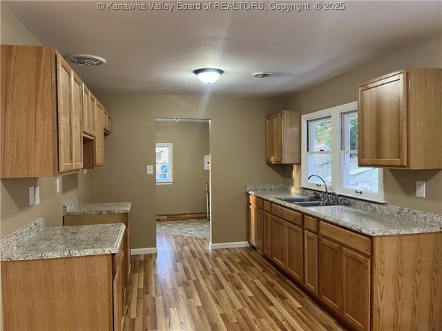 kitchen featuring light stone countertops, sink, and light wood-type flooring