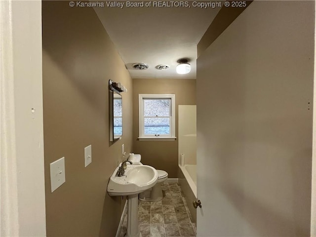 bathroom featuring a tub to relax in and toilet