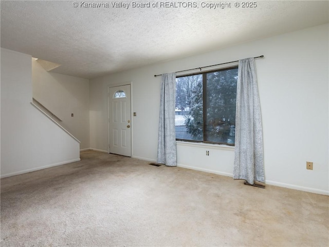 foyer entrance with light carpet and a textured ceiling