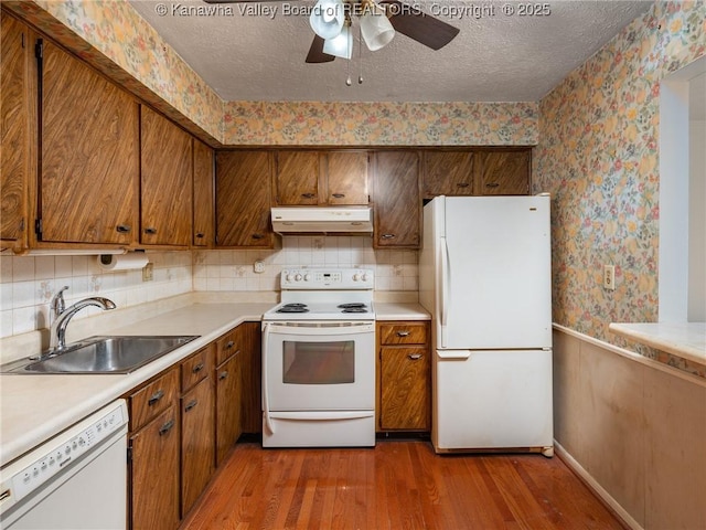 kitchen with white appliances, hardwood / wood-style floors, sink, and a textured ceiling