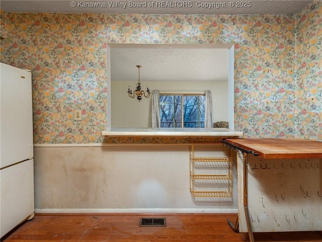 interior space featuring butcher block counters, decorative light fixtures, a textured ceiling, white fridge, and hardwood / wood-style flooring