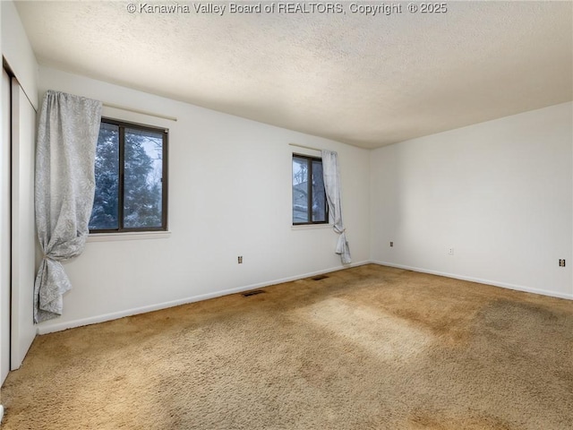 unfurnished room featuring carpet and a textured ceiling