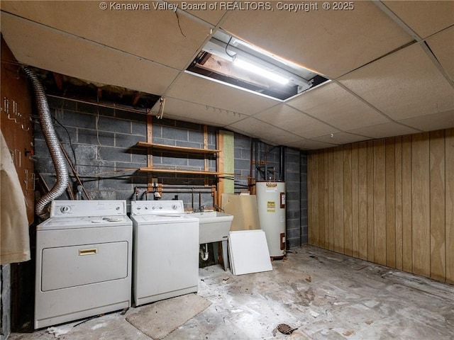 clothes washing area featuring sink, washing machine and dryer, water heater, and wood walls