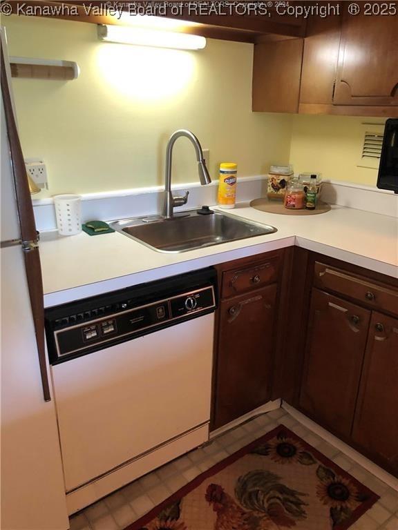 kitchen with dark brown cabinets, sink, and white dishwasher