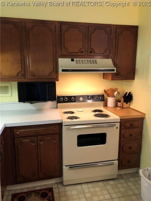 kitchen featuring extractor fan, white electric range, and dark brown cabinets