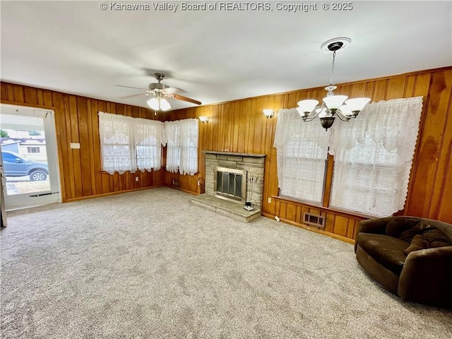 living room with a stone fireplace, carpet, and wood walls