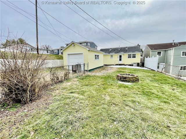 back of house with a garage, a fire pit, and a lawn