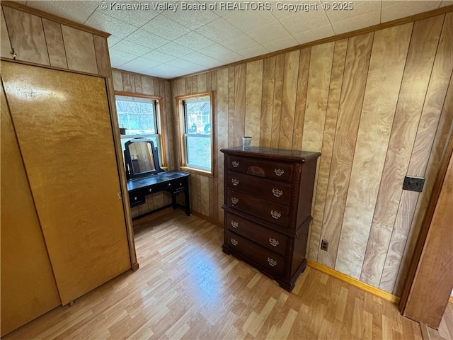 interior space featuring crown molding, wood walls, and light wood-type flooring