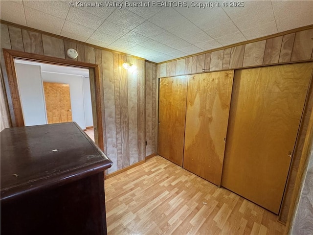 hallway with crown molding, wooden walls, and light hardwood / wood-style floors