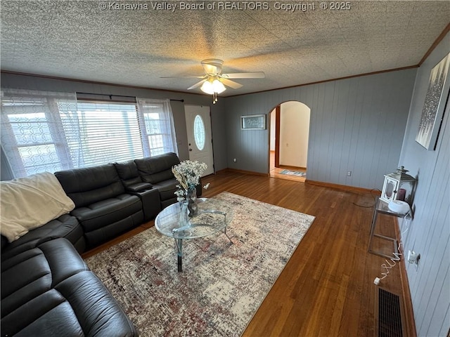 living room featuring ceiling fan, ornamental molding, dark hardwood / wood-style flooring, and a textured ceiling