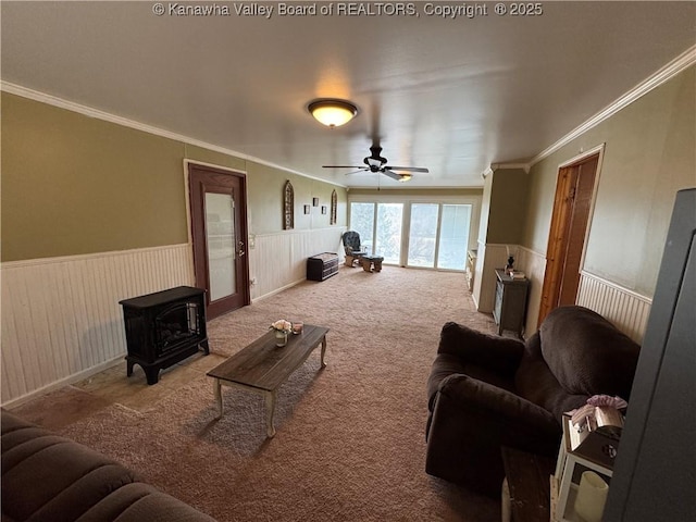 living room featuring crown molding, carpet floors, ceiling fan, and a wood stove