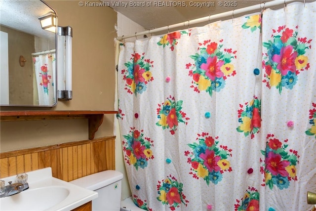 bathroom with vanity, curtained shower, toilet, and a textured ceiling