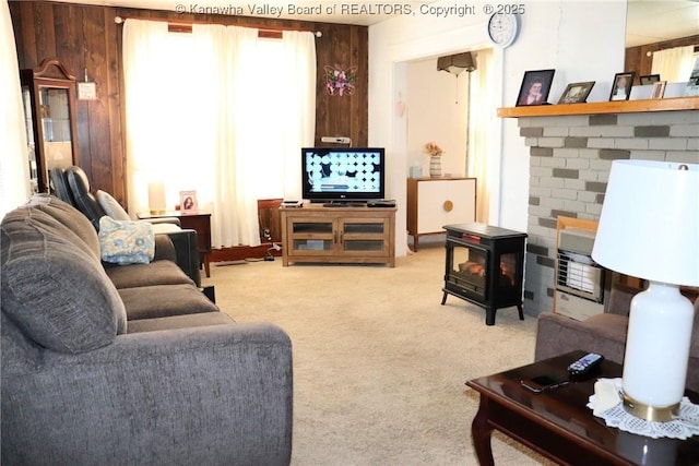 living room with a wood stove, light colored carpet, and wooden walls