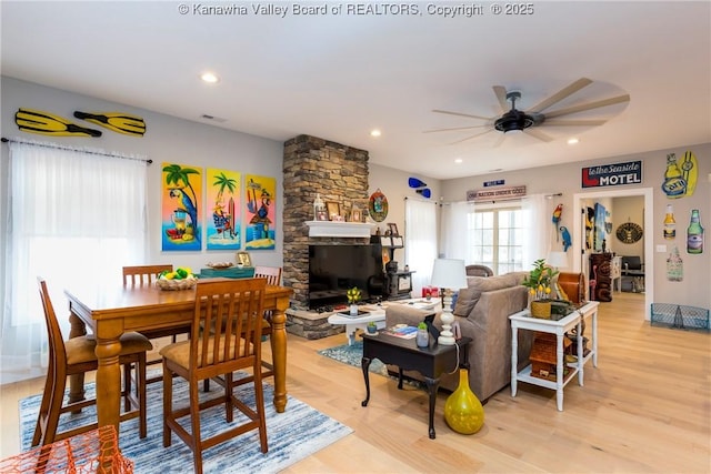 living room with a fireplace, light hardwood / wood-style flooring, and ceiling fan