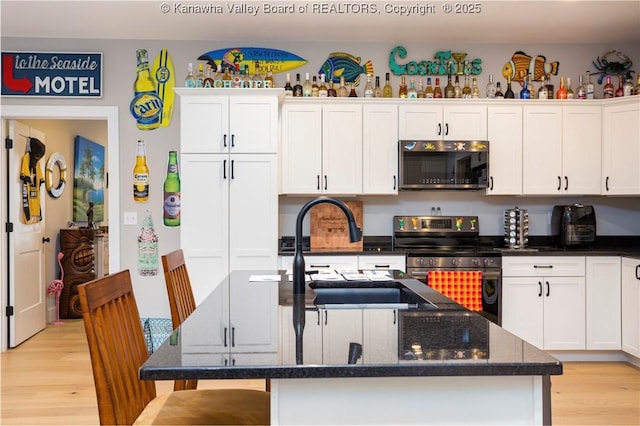 kitchen featuring stainless steel appliances, an island with sink, sink, and white cabinets