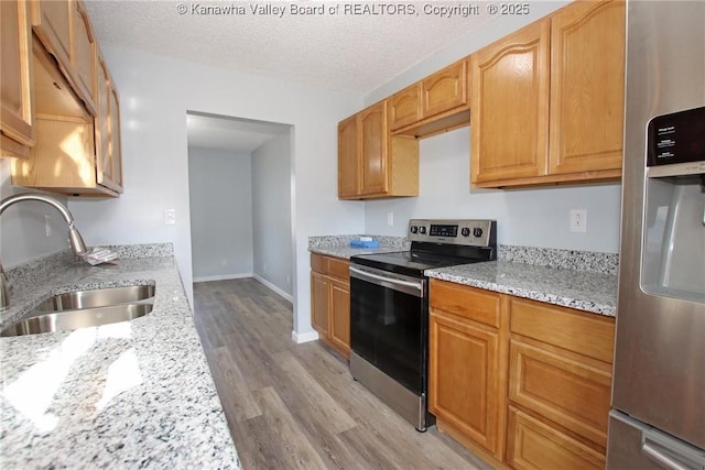 kitchen featuring light stone countertops, appliances with stainless steel finishes, sink, and a textured ceiling