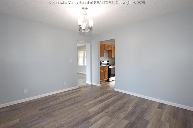 unfurnished room with an inviting chandelier, dark hardwood / wood-style floors, and a textured ceiling