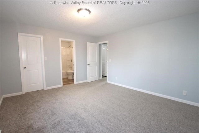 unfurnished bedroom featuring ensuite bathroom, carpet, and a textured ceiling