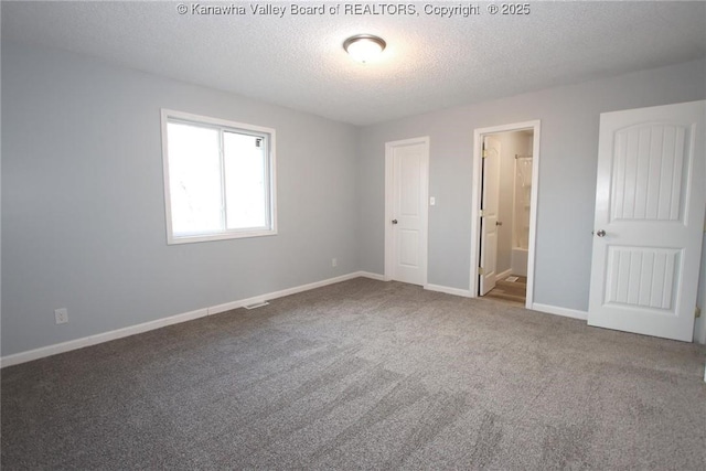 unfurnished bedroom with carpet floors, a textured ceiling, and ensuite bathroom