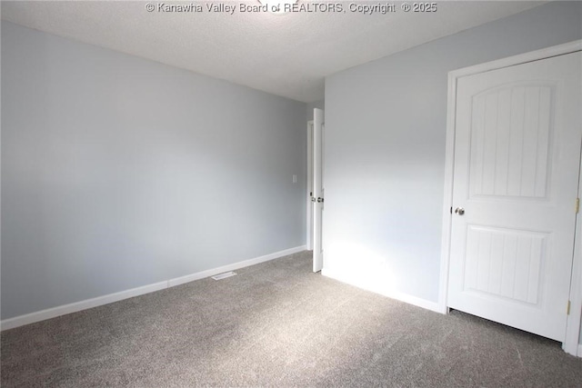 unfurnished bedroom featuring a textured ceiling and dark colored carpet