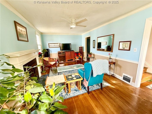 living room with ornamental molding, wood-type flooring, and ceiling fan