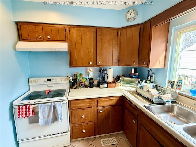 kitchen featuring sink, light tile patterned floors, and electric range