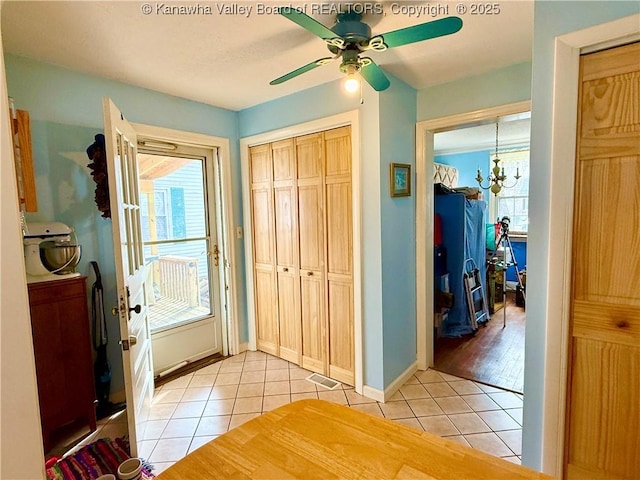 foyer entrance featuring light tile patterned flooring and ceiling fan with notable chandelier