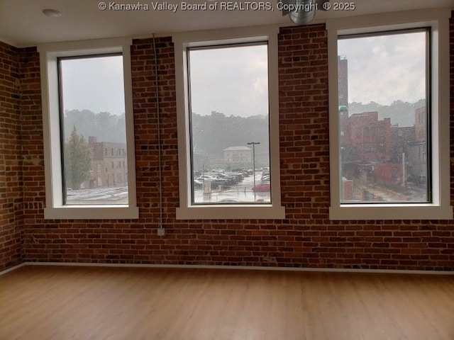 spare room featuring hardwood / wood-style flooring and brick wall