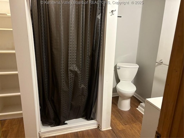 bathroom featuring walk in shower, hardwood / wood-style floors, and toilet