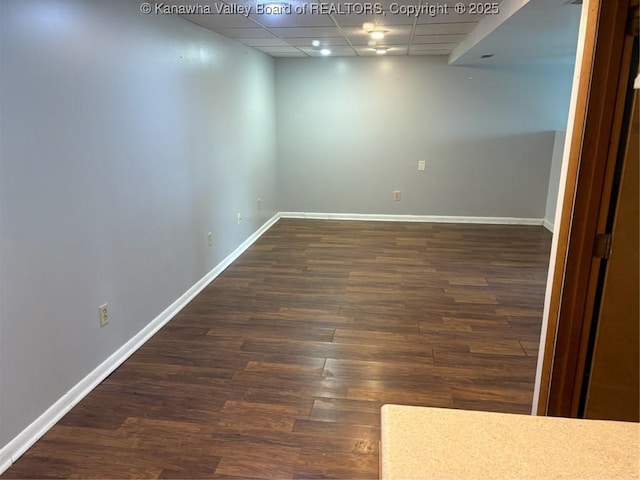 basement with a paneled ceiling and dark hardwood / wood-style floors