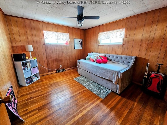 bedroom featuring ceiling fan, wooden walls, and hardwood / wood-style floors