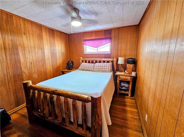 bedroom featuring ceiling fan, wooden walls, and dark hardwood / wood-style floors