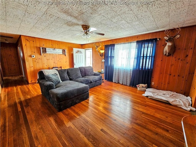 living room featuring wooden walls, hardwood / wood-style floors, and ceiling fan