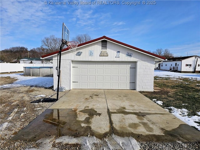 snow covered garage featuring a fenced in pool