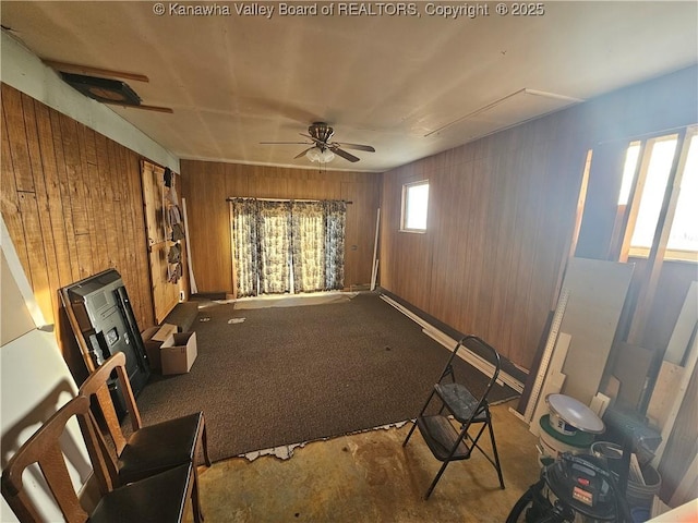 interior space featuring ceiling fan and wood walls