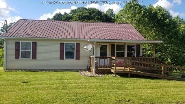 back of property featuring a wooden deck and a yard