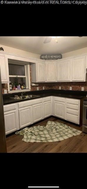 kitchen with white cabinetry, dark wood-type flooring, and range