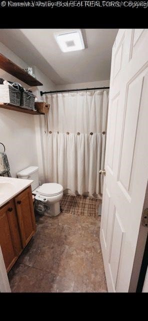 bathroom featuring toilet, vanity, and a shower with shower curtain