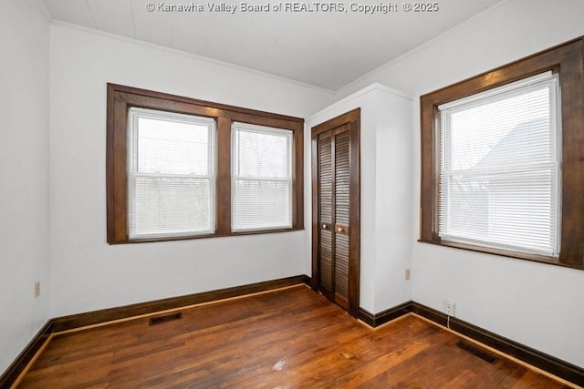 spare room featuring crown molding and dark wood-type flooring