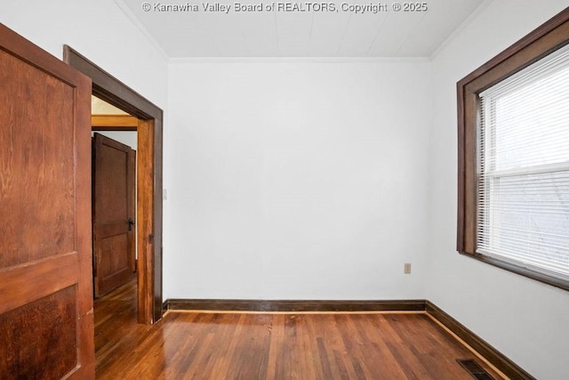 empty room featuring ornamental molding and dark hardwood / wood-style flooring