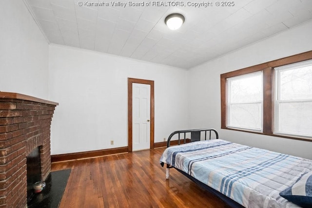 bedroom featuring a fireplace, ornamental molding, and dark hardwood / wood-style floors