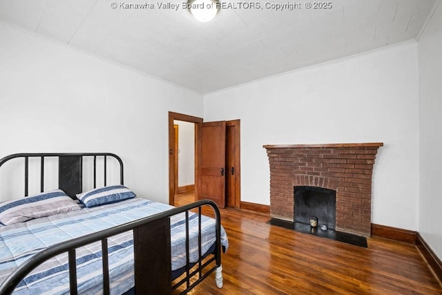 bedroom with a brick fireplace, hardwood / wood-style flooring, and ornamental molding