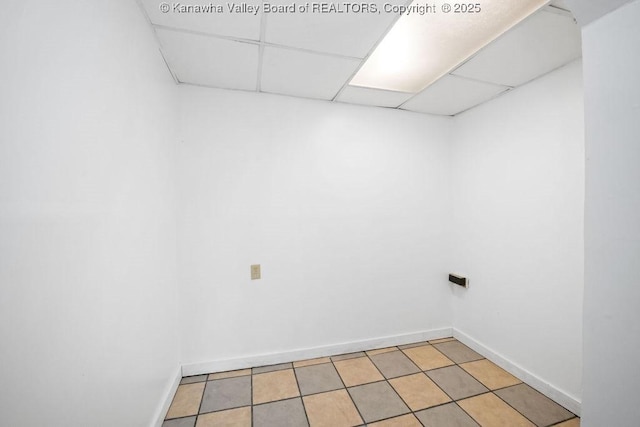 tiled empty room featuring a drop ceiling