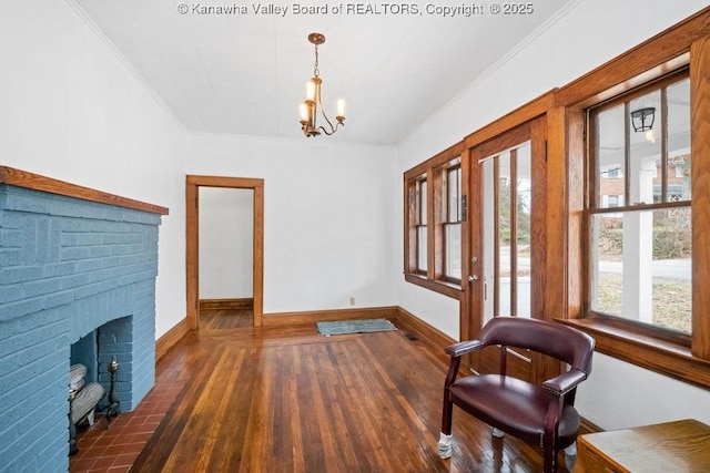 sitting room with dark hardwood / wood-style flooring, a fireplace, ornamental molding, and an inviting chandelier