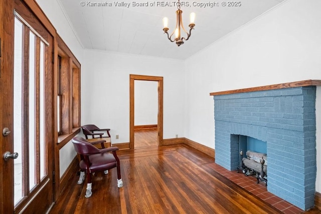 sitting room with dark wood-type flooring, crown molding, a brick fireplace, and a notable chandelier