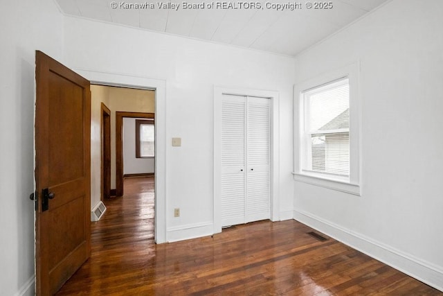 unfurnished bedroom featuring dark hardwood / wood-style flooring and a closet